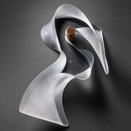 transparent abstract bird shaped hanging wall mounted sculpture with a clear front and back and frosted curling side hand made from cast glass and suspended on a round peg shaped teak fitting