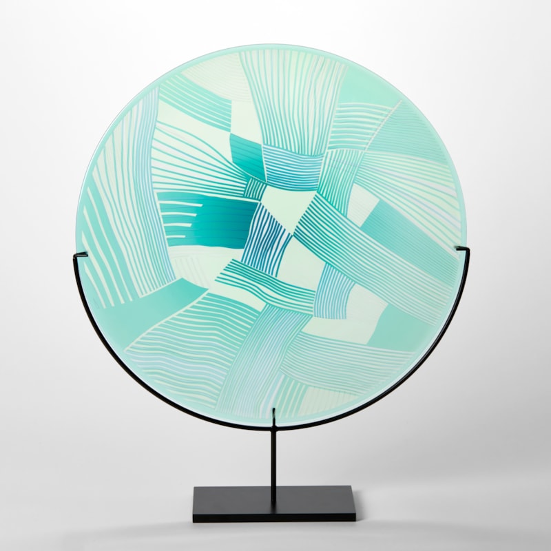 aqua and jade translucent round glass rondel with abstract patchwork landscape cutting on the surface handmade from glass and presented on a matt black steel stand