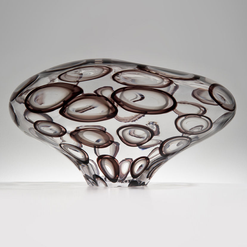 abstract wide-shaped decorative glass sculpture in clear with large dark brown circle patterning throughout