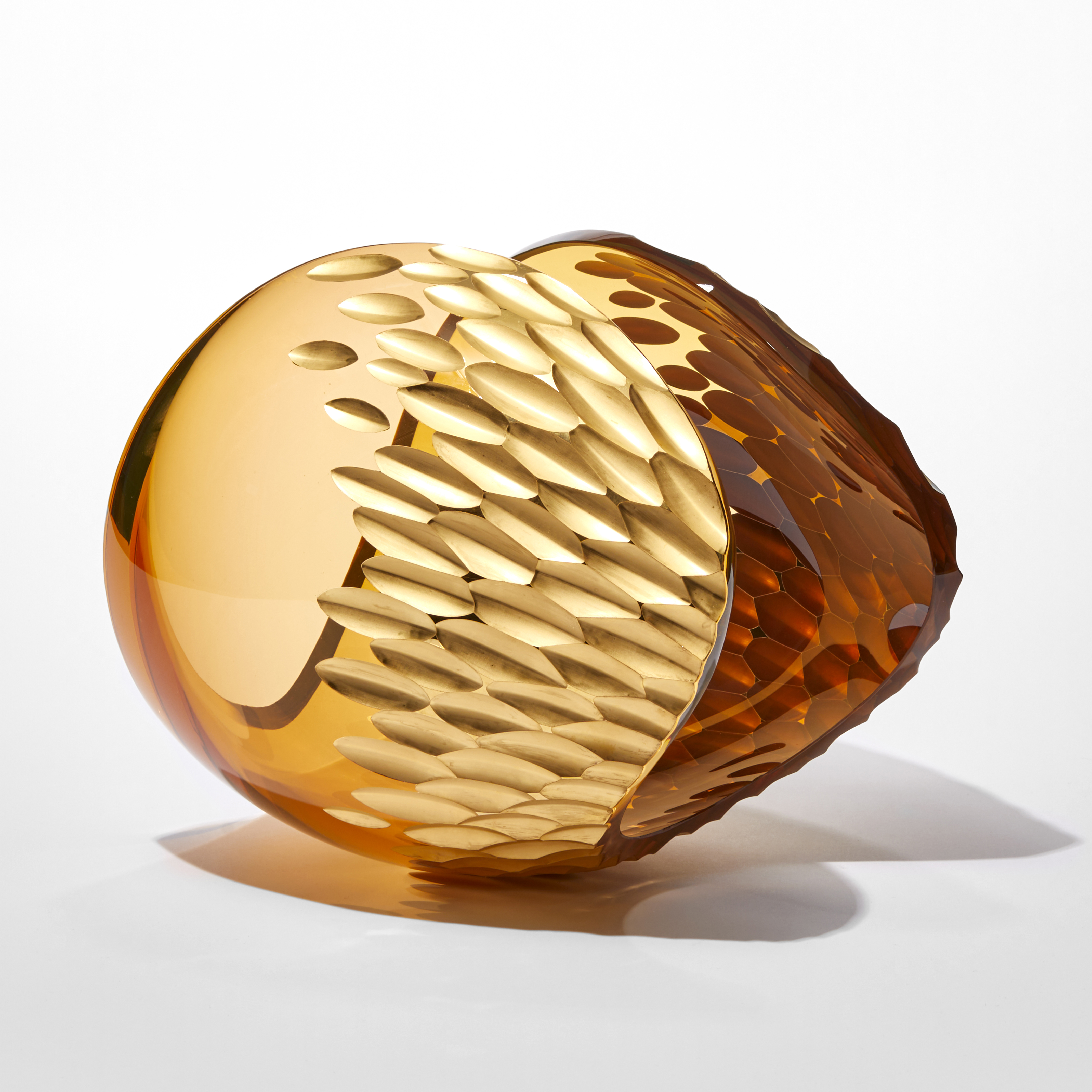 rich amber peach transparent ovoid sculpture with sweeping cut away section creating a curved traversing rim with repeat leaf shaped patterned incised section in gold hand made from glass
