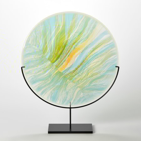 translucent green yellow and aqua round disc on a matt black stand with abstract cut lines on the surface hand made from glass
