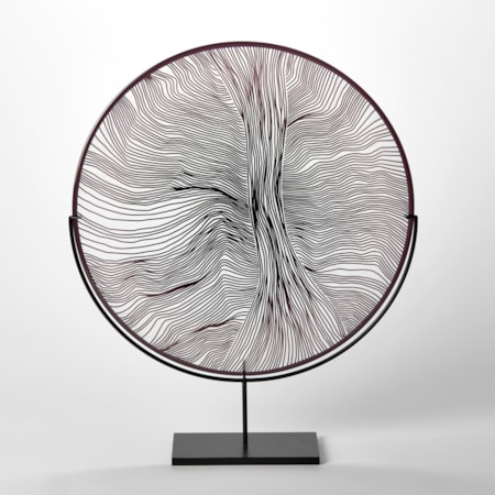 round plate in clear and black with cut abstract surface linear patterns hand made from glass held aloft on a steel matt black stand