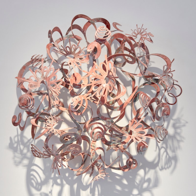 sun inspired wall hung artwork made from patinated brass consisting of swirls spirals curls and shapes that emerge from the wall