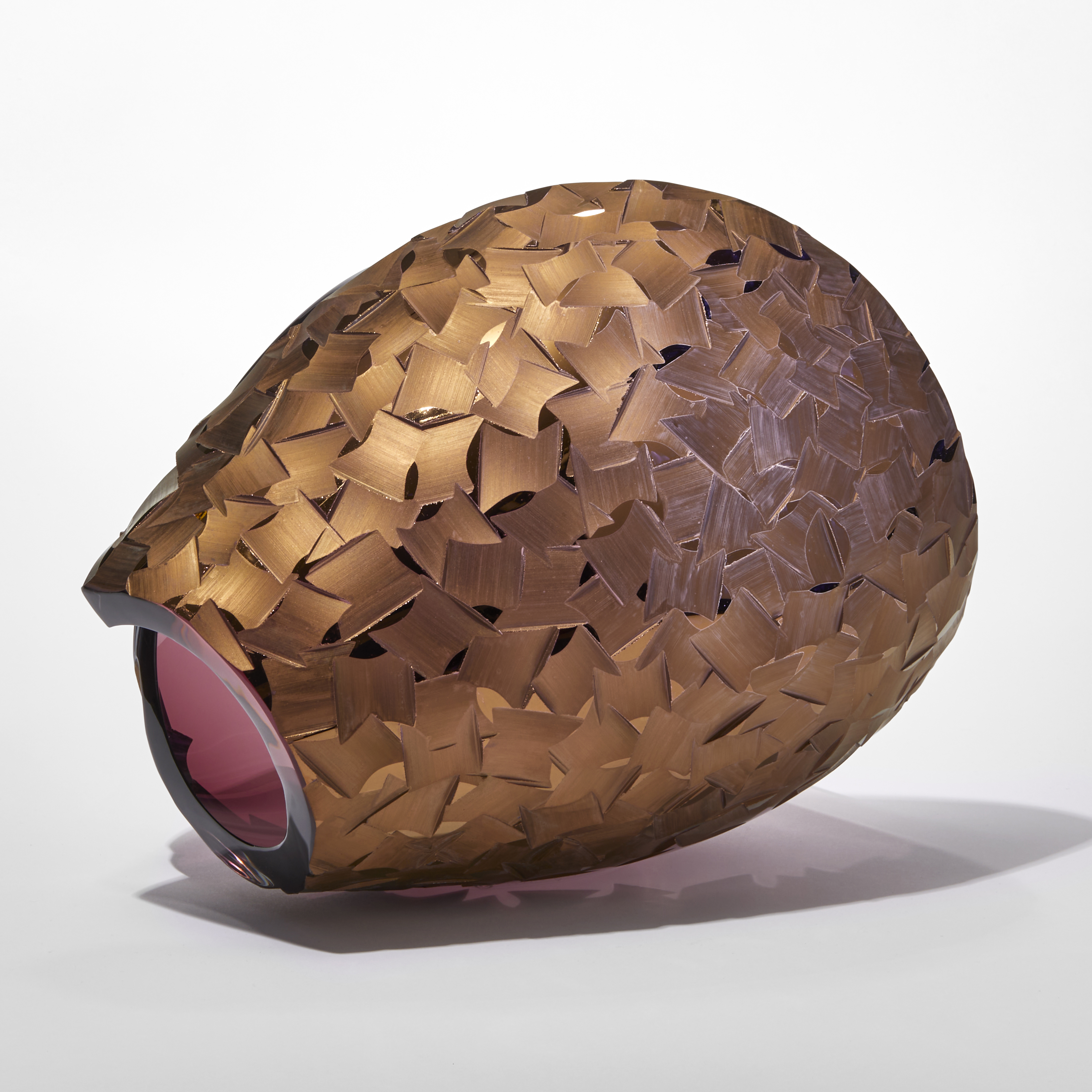 transparent aubergine ovoid with sweeping cut away section leaving a dramatic curved edge with one side covered in a deep incised cut organic pattern finished in gold hand made from glass