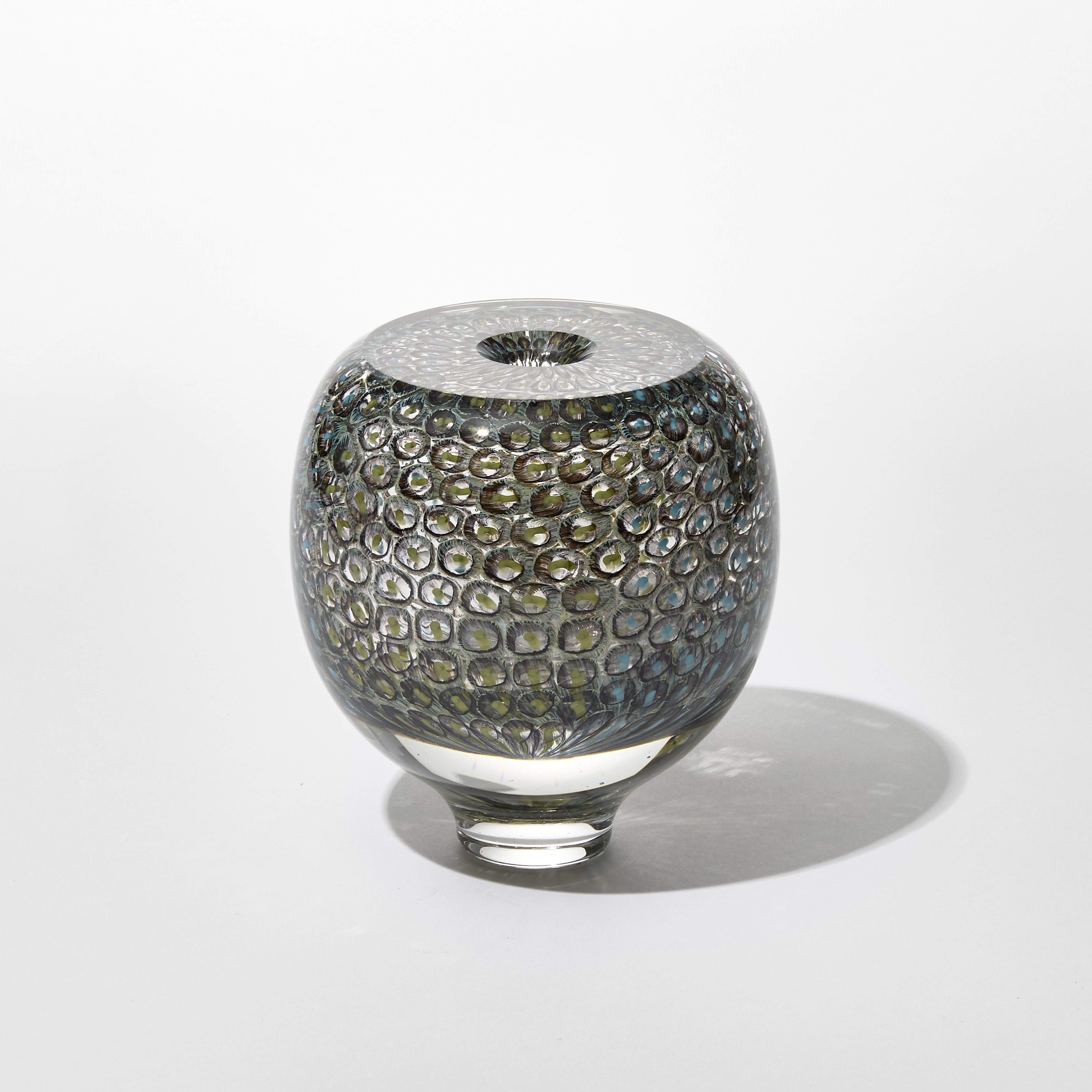 round transparent vase with small circular repeat pattern trapped inside in dark sage green and turquoise hand made from blown glass
