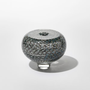 low round transparent vase with incased repeat round small circle and dot pattern in dark green and teal with a flat top surface and small central middle hole hand made from glass