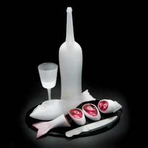 still life blown and sculpted glass art piece of cut fish, knife, bottle and glass in white