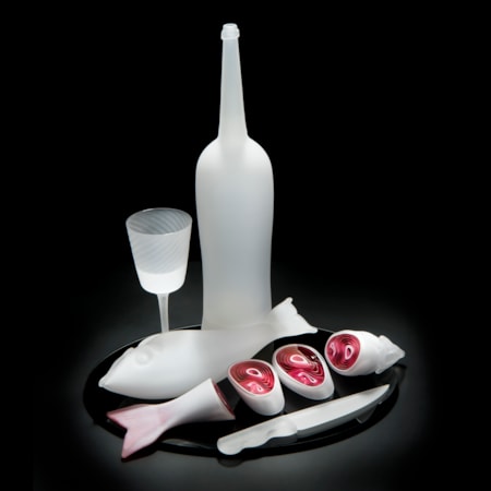 still life blown and sculpted glass art piece of cut fish, knife, bottle and glass in white