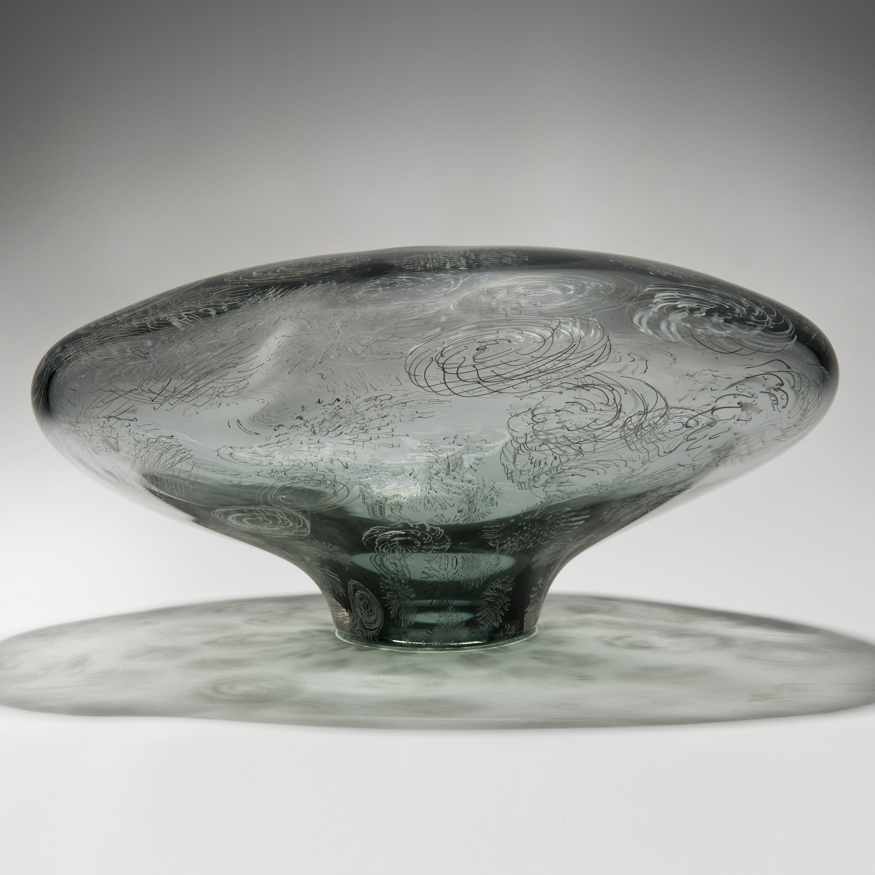 contemporary oval shaped art glass sculpture in light grey and green with swirl patterns