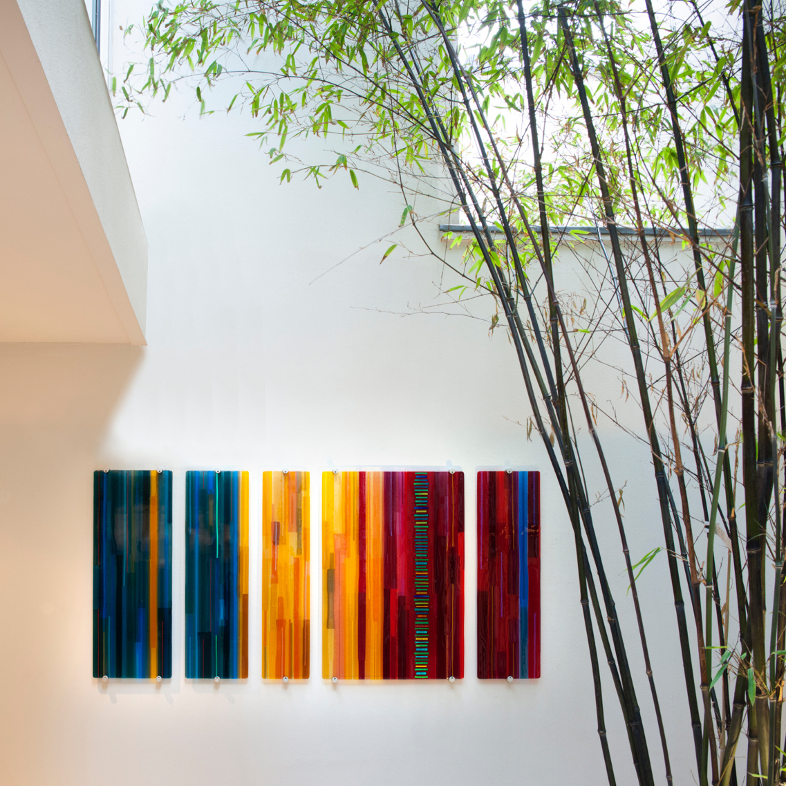 series of five fused glass wall mounted panels in dark blue red and orange shades