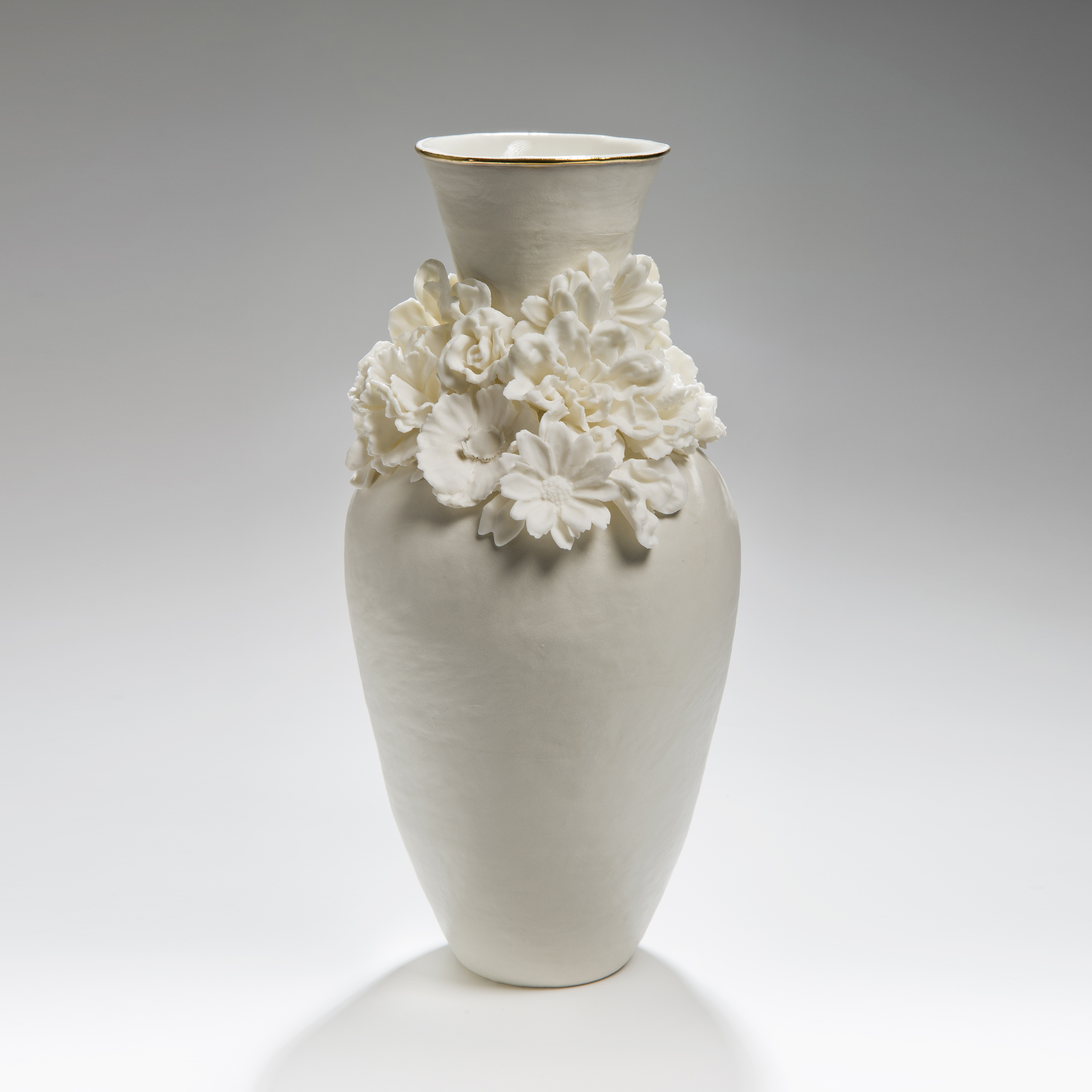 modern ceramic vase sculpture of a classical style in white with flowers sculpted at neck