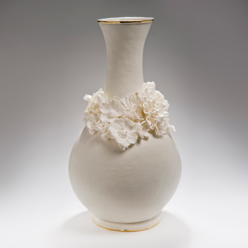 white ceramic vase with wide base and long neck and sculpted flowers