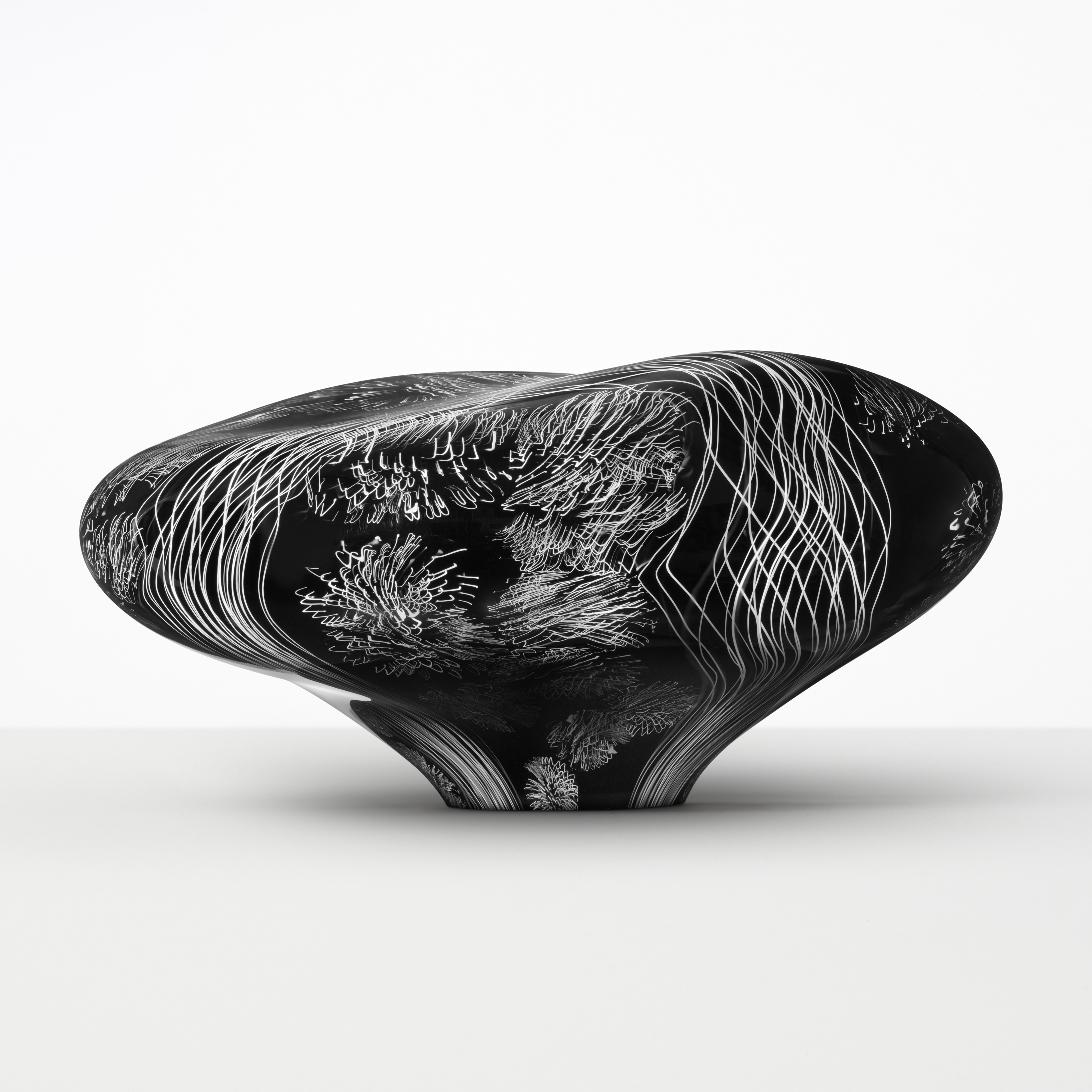 abstract brain-shaped clear glass sculpture in black with white etched patterning throughout 