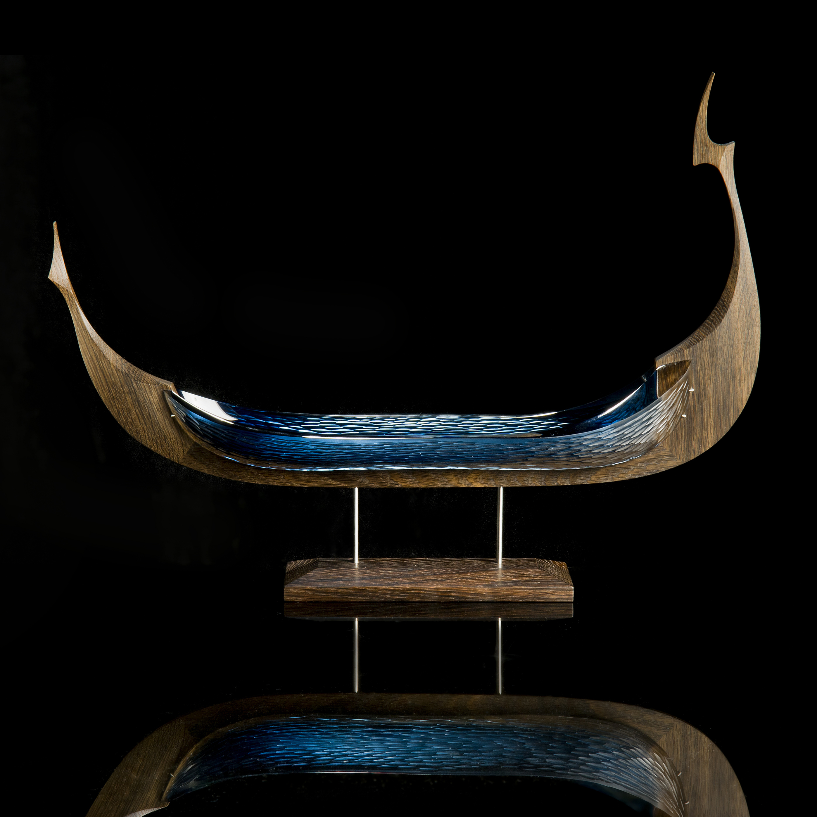 wood and glass sculpture of viking ship in green and brown on wooden base