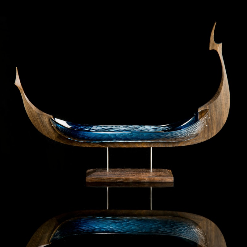 wood and glass sculpture of viking ship in green and brown on wooden base