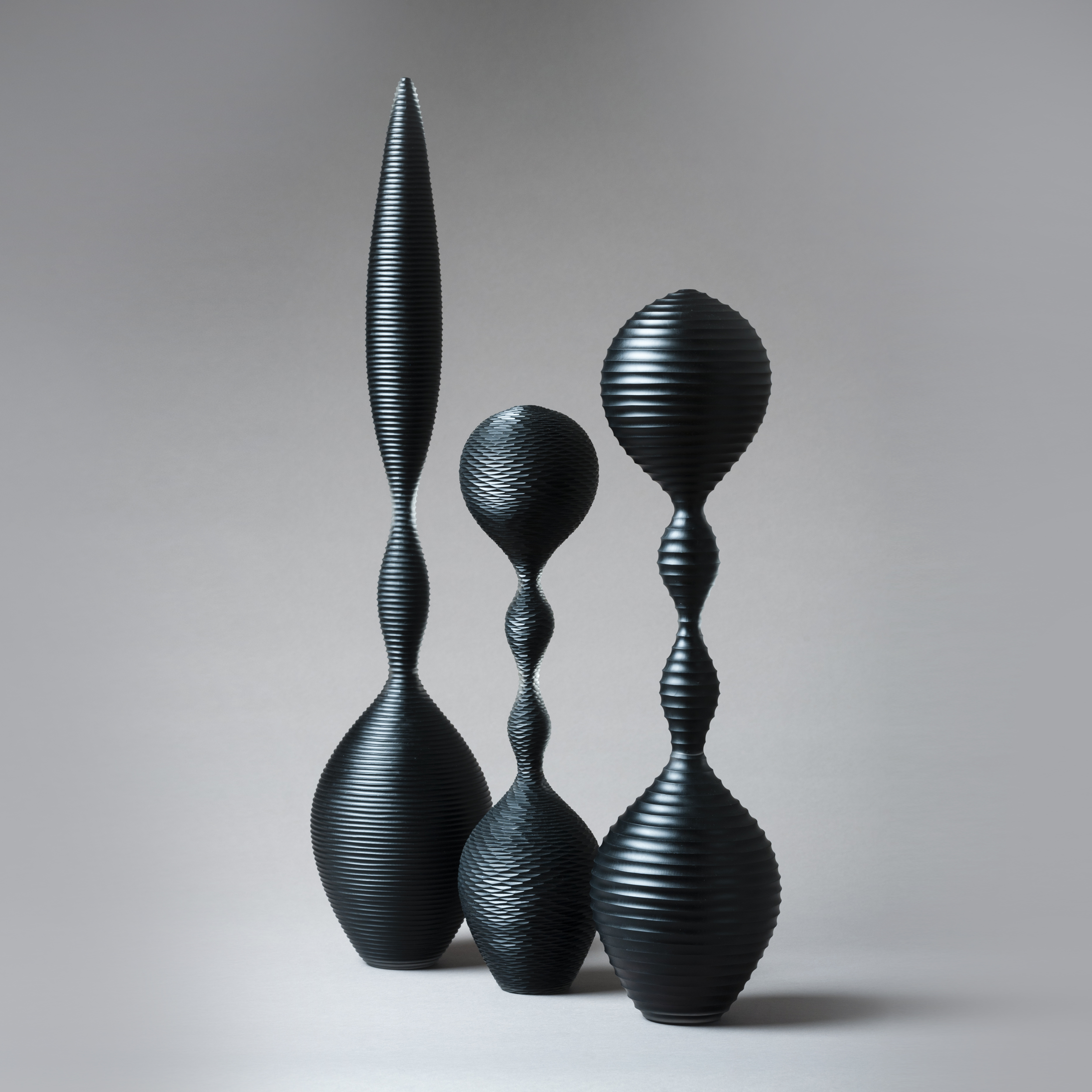 a trio of abstract black sculpted glass ornaments in different sizes