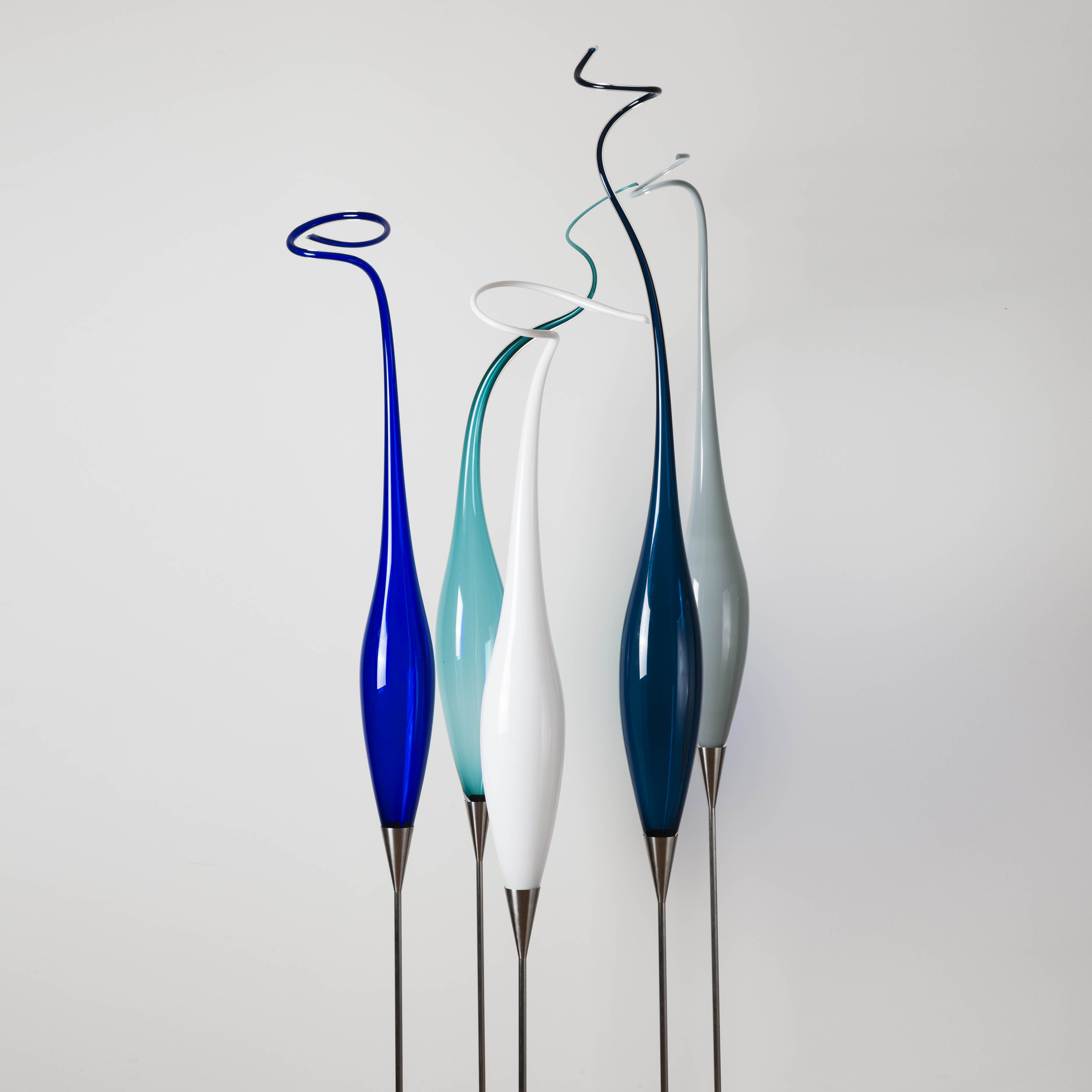 tall thin abstract glass sculptures on steel base in white blue turquoise dark green and grey