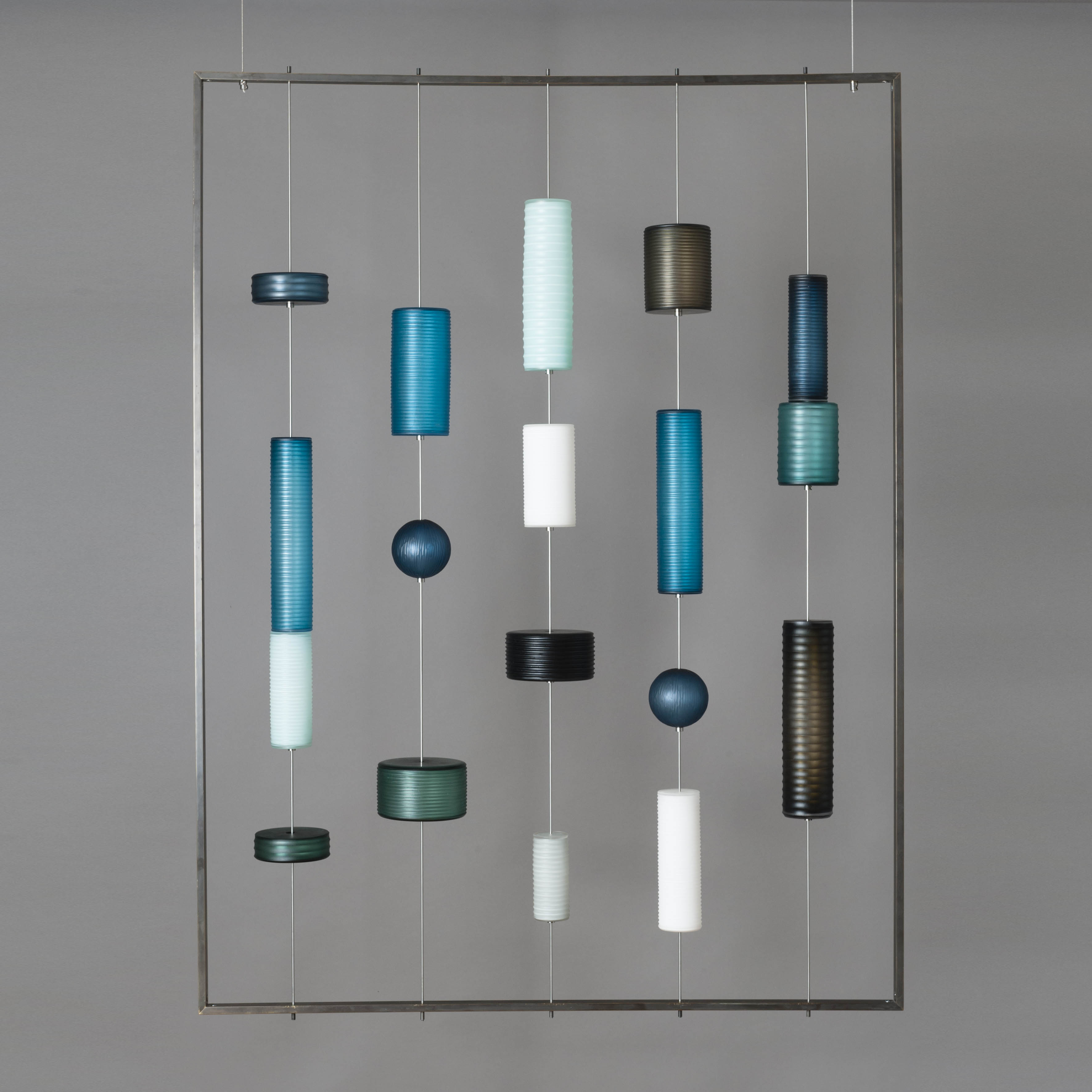modern glass wall art with pieces held by wire on hollow steel frame