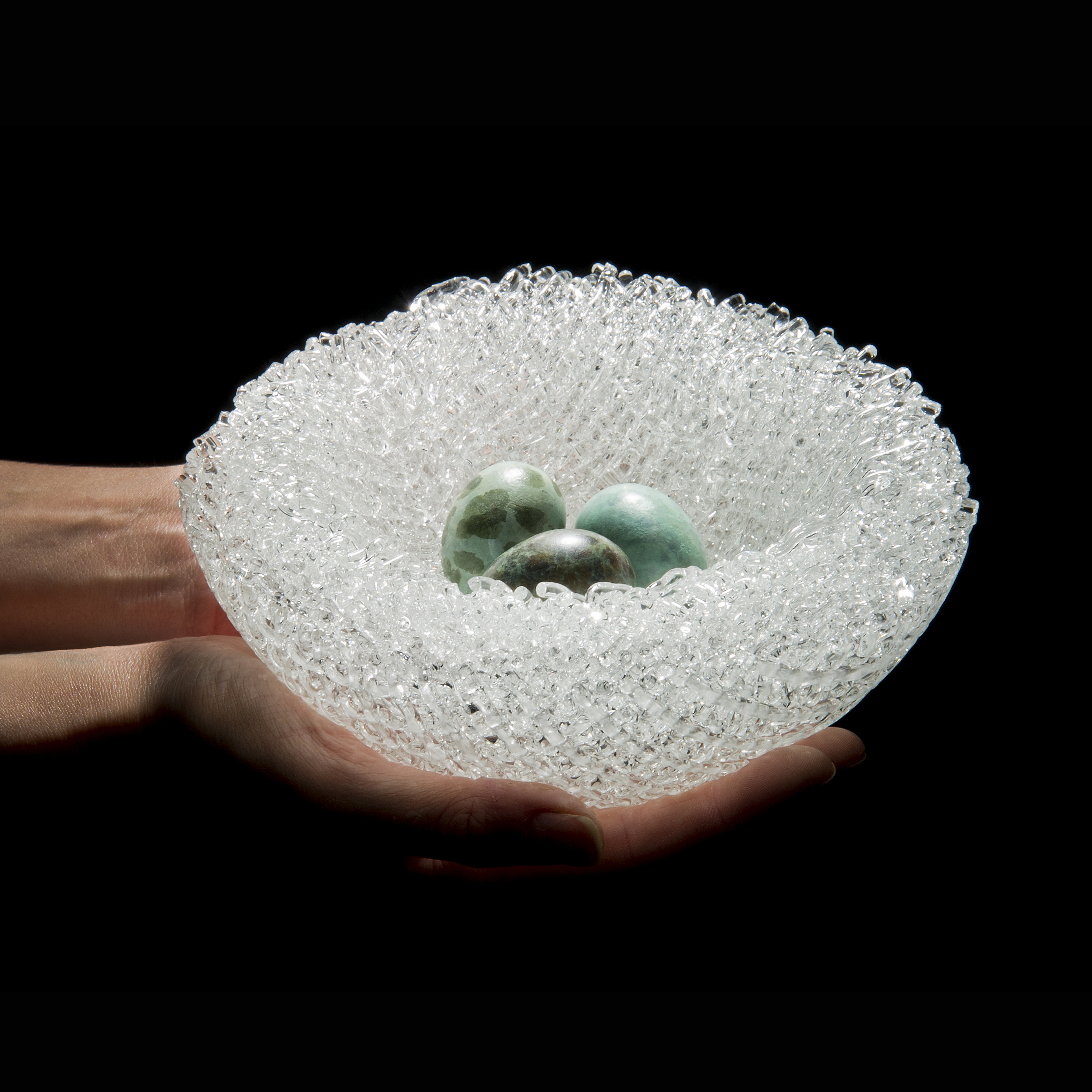 modern glass sculpture of kiln formed glass cane with patinated cast bronze eggs