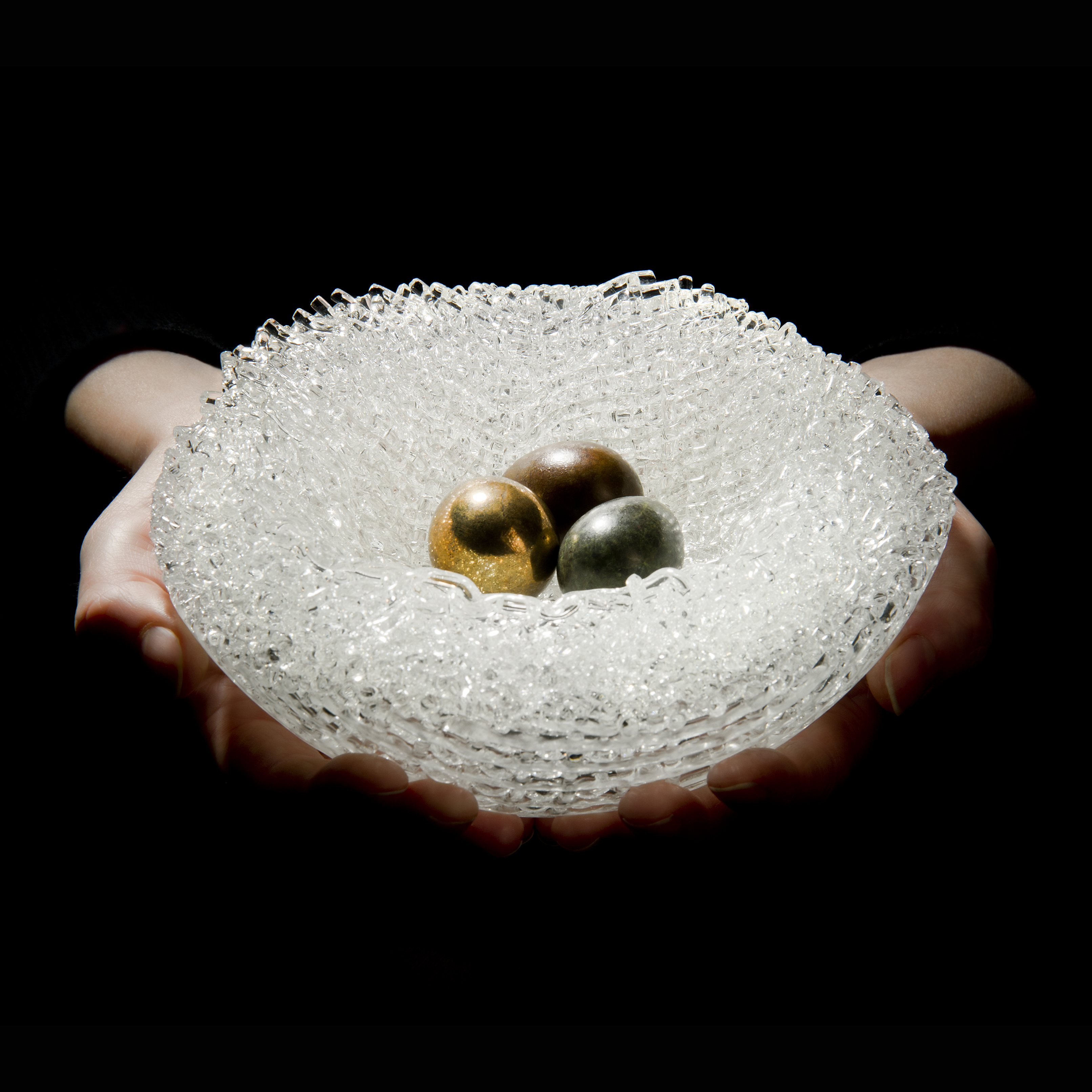 experimental kiln formed art glass sculpture resembling birds nest with three bronze eggs in centre