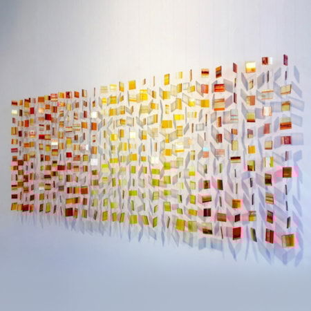 wall hanging glass installation made from small orange, yellow and red pieces