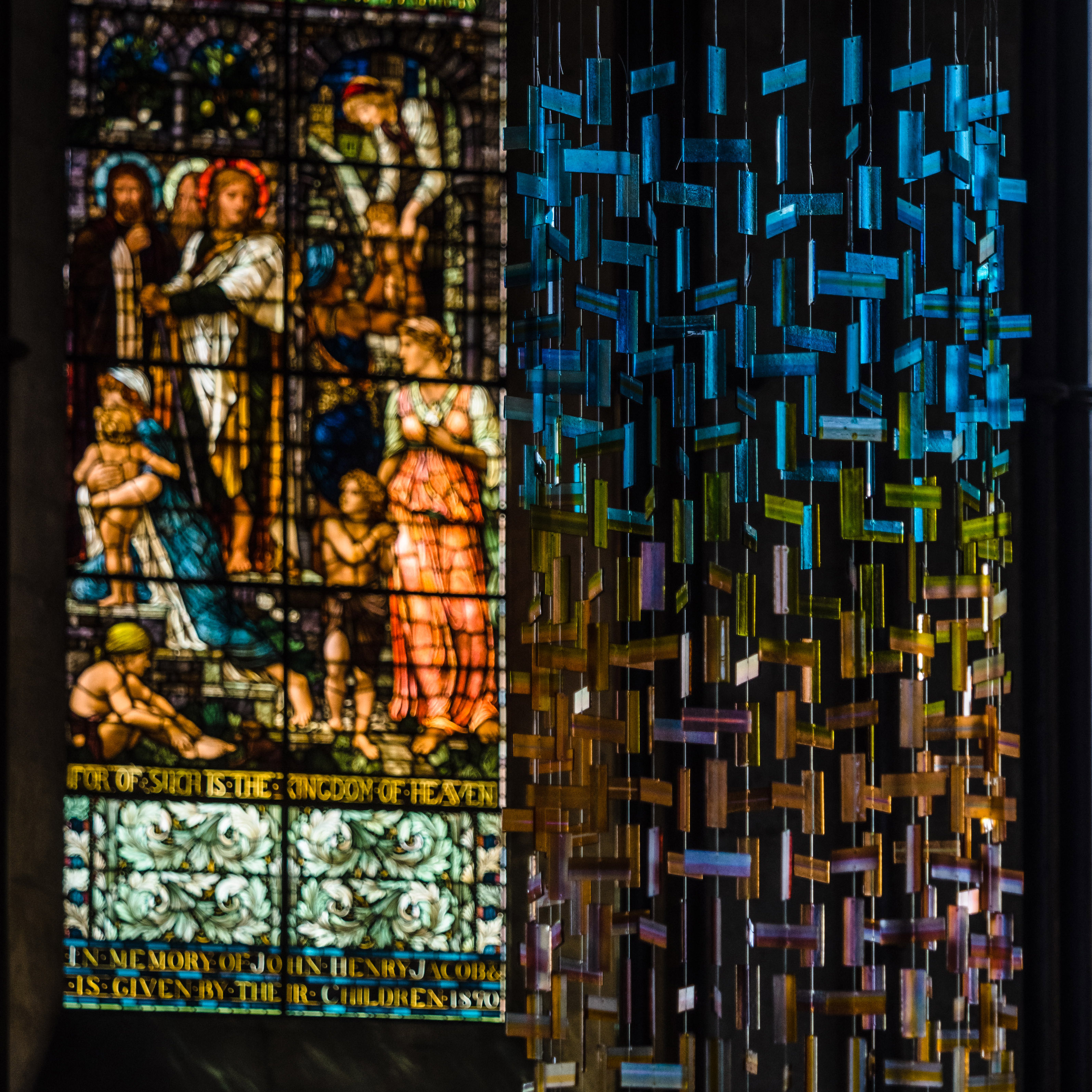 hanging glass installation from handmade fused glass components complementing church stained glass window colours