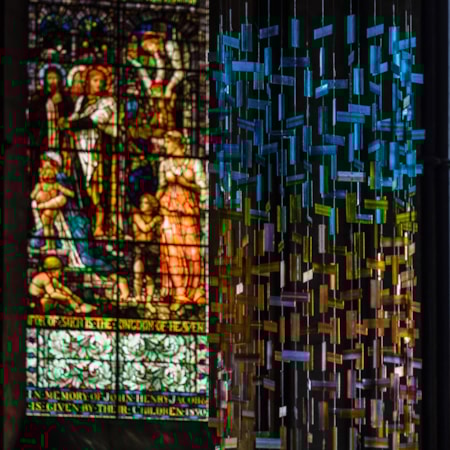 hanging glass installation from handmade fused glass components complementing church stained glass window colours