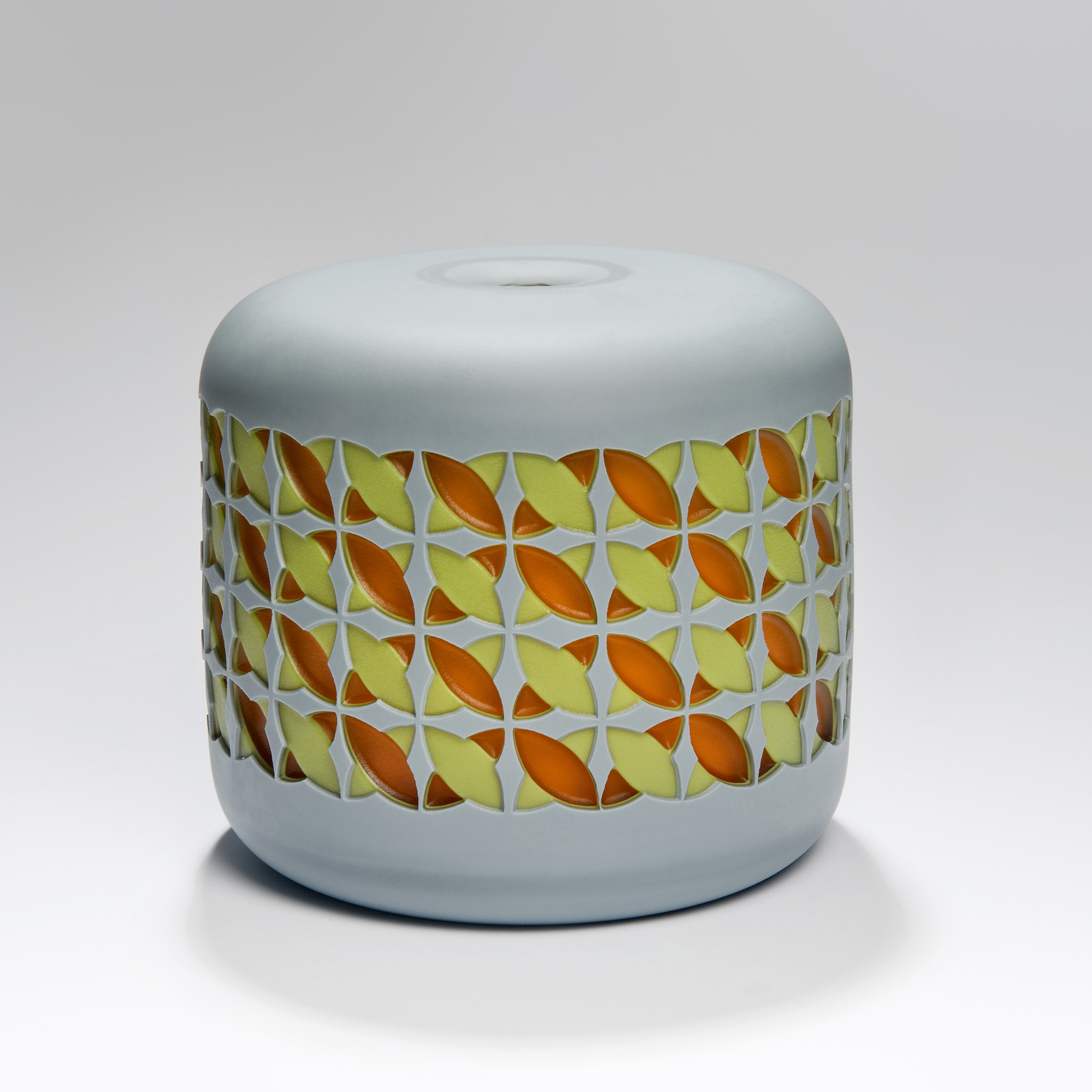 round cake shaped glass sculpture in grey with yellow and orange pattern