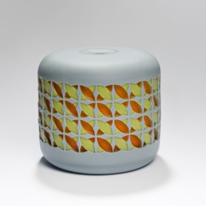round cake shaped glass sculpture in grey with yellow and orange pattern