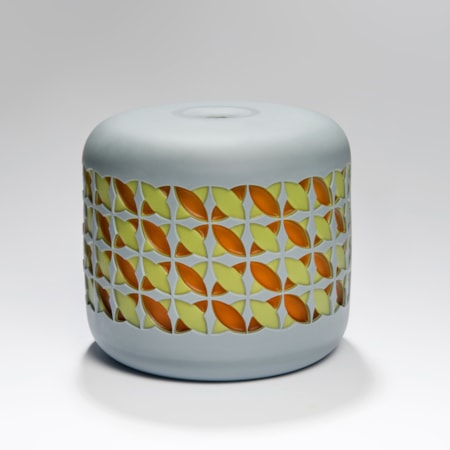 round cake shaped glass sculpture in grey with yellow and orange pattern