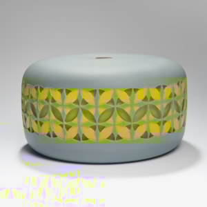 round cake shaped glass sculpture in grey with yellow and gren pattern