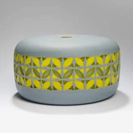 round cake shaped glass sculpture in grey with yellow and gren pattern