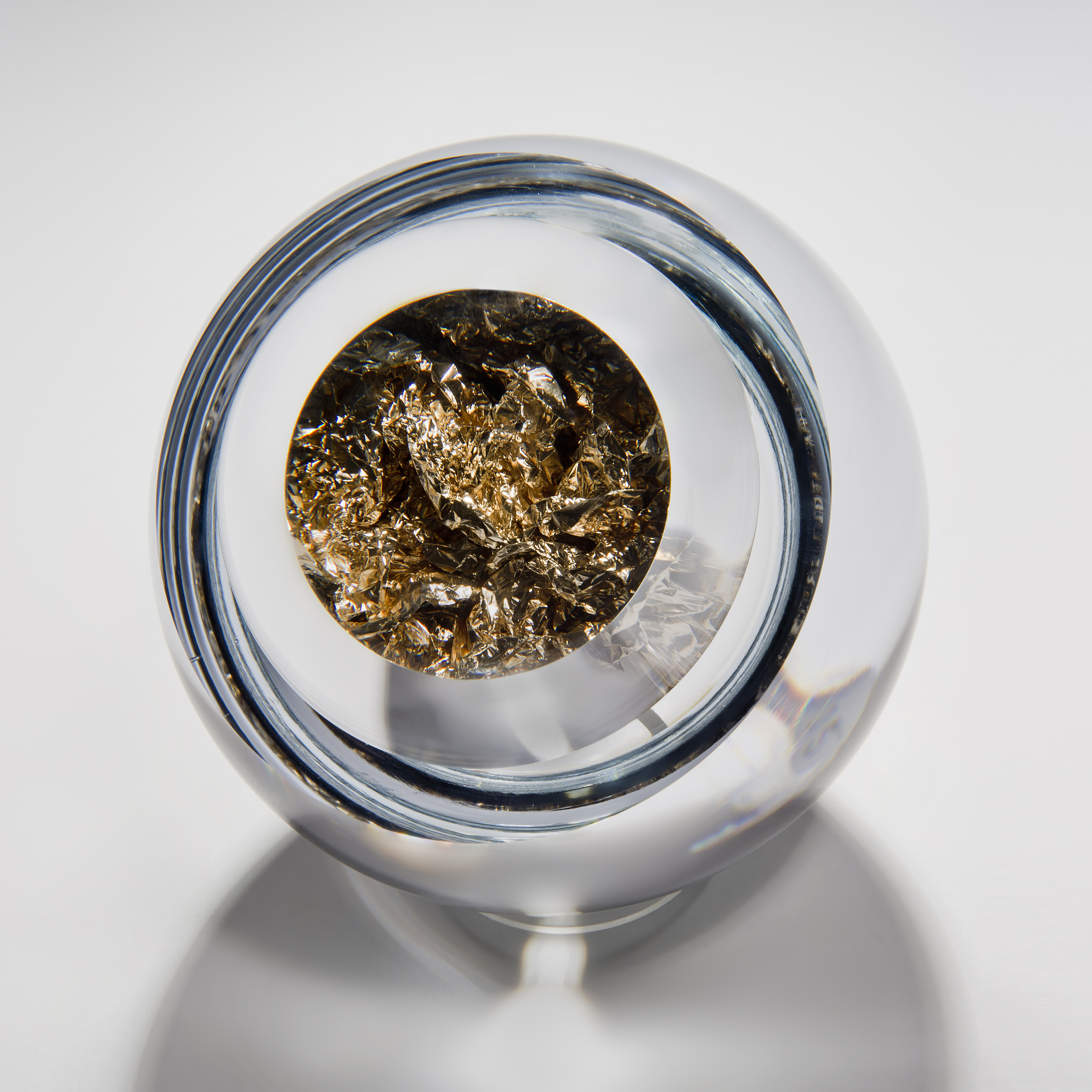 modern art glass sculpture of round object with hole in clear glass and platinum