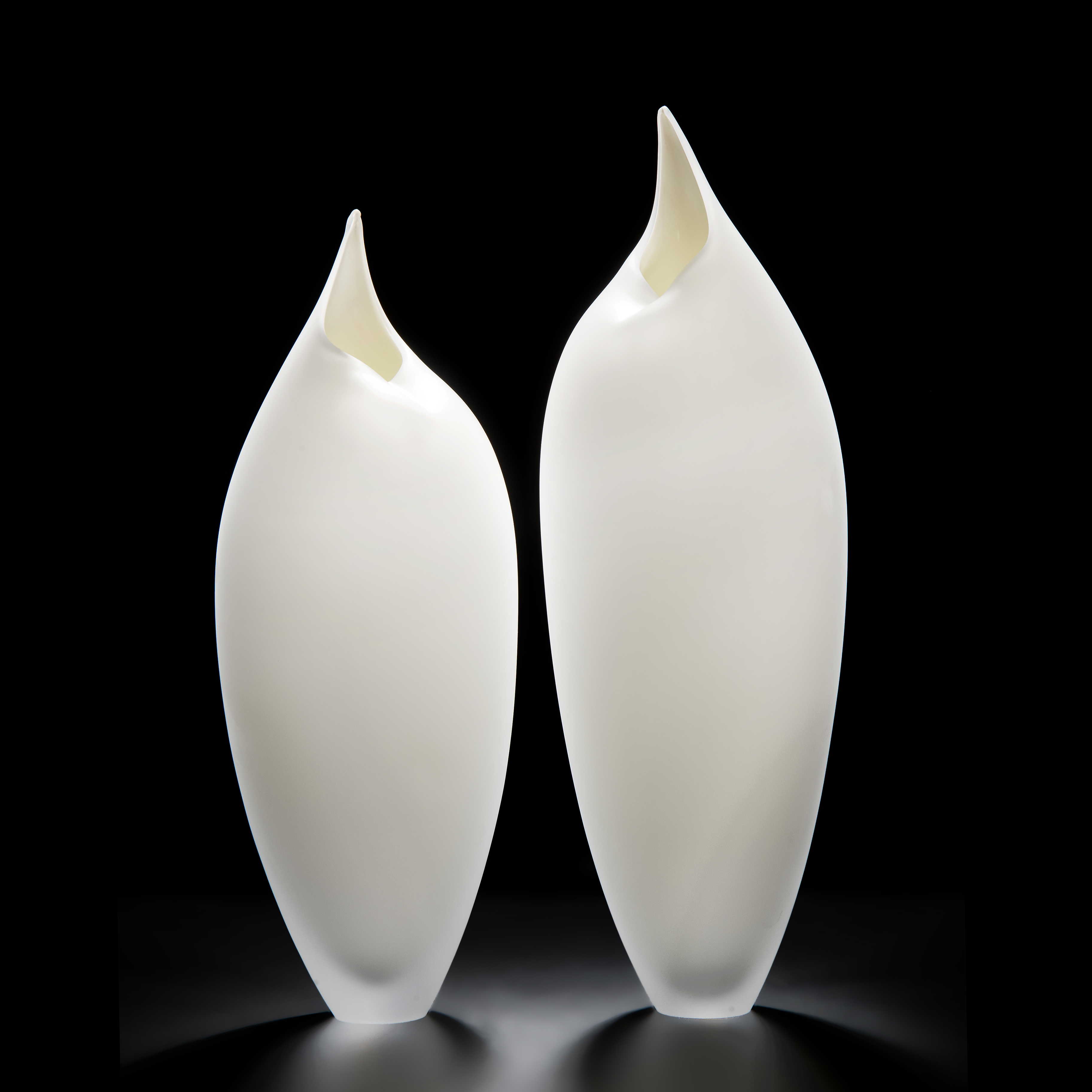 two minimalist art-glass sculptures in white shaped like birds