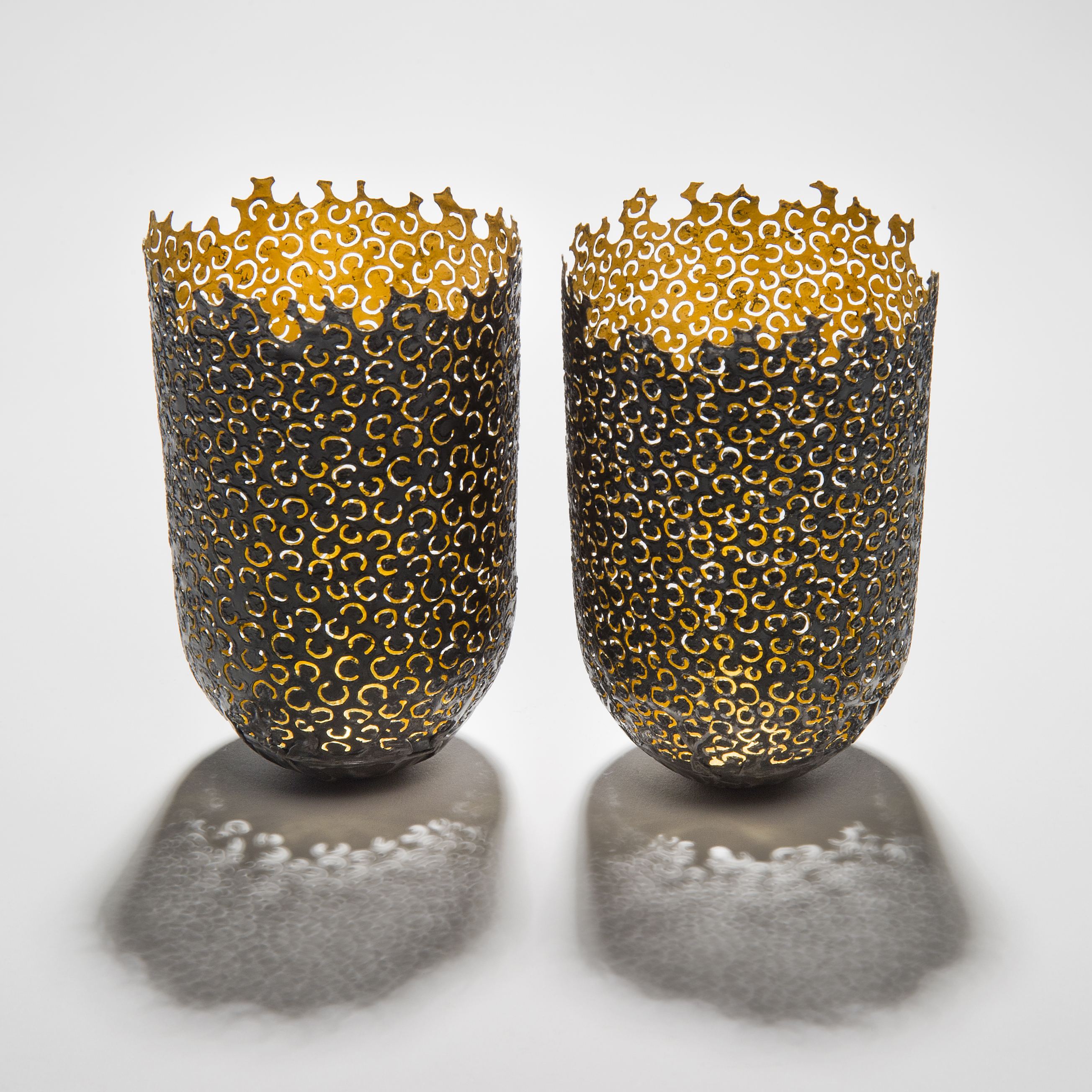 two decorative reformed steel cans with gold inlay and horseshoe shaped patterned exterior