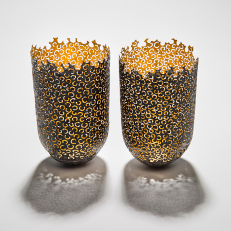two decorative reformed steel cans with gold inlay and horseshoe shaped patterned exterior