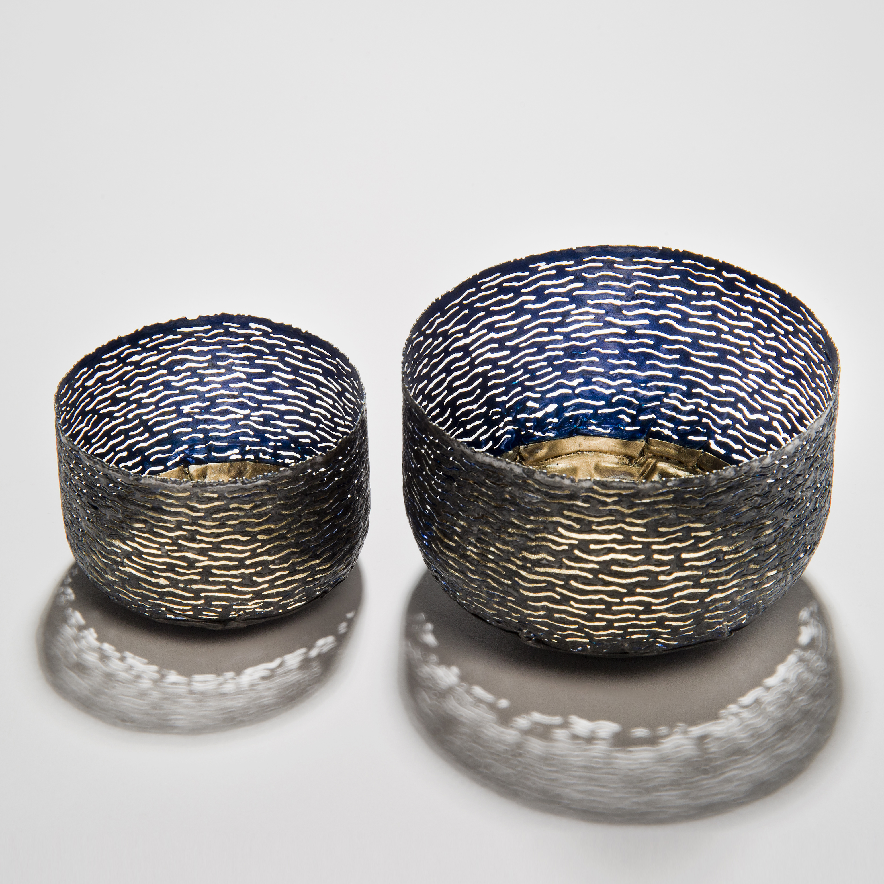 two decorative reformed steel can bowls in blue and grey with gold patterned interior and exterior 