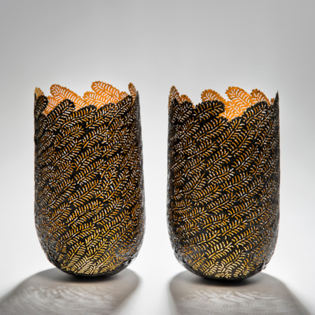 two sculpted open top vessels made from steel and gold cut leaf shapes arranged together