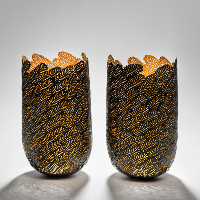two sculpted open top vessels made from steel and gold cut leaf shapes arranged together