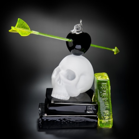 art glass still life sculpture of white skull on black base with neon green arrow through black apple resting on top