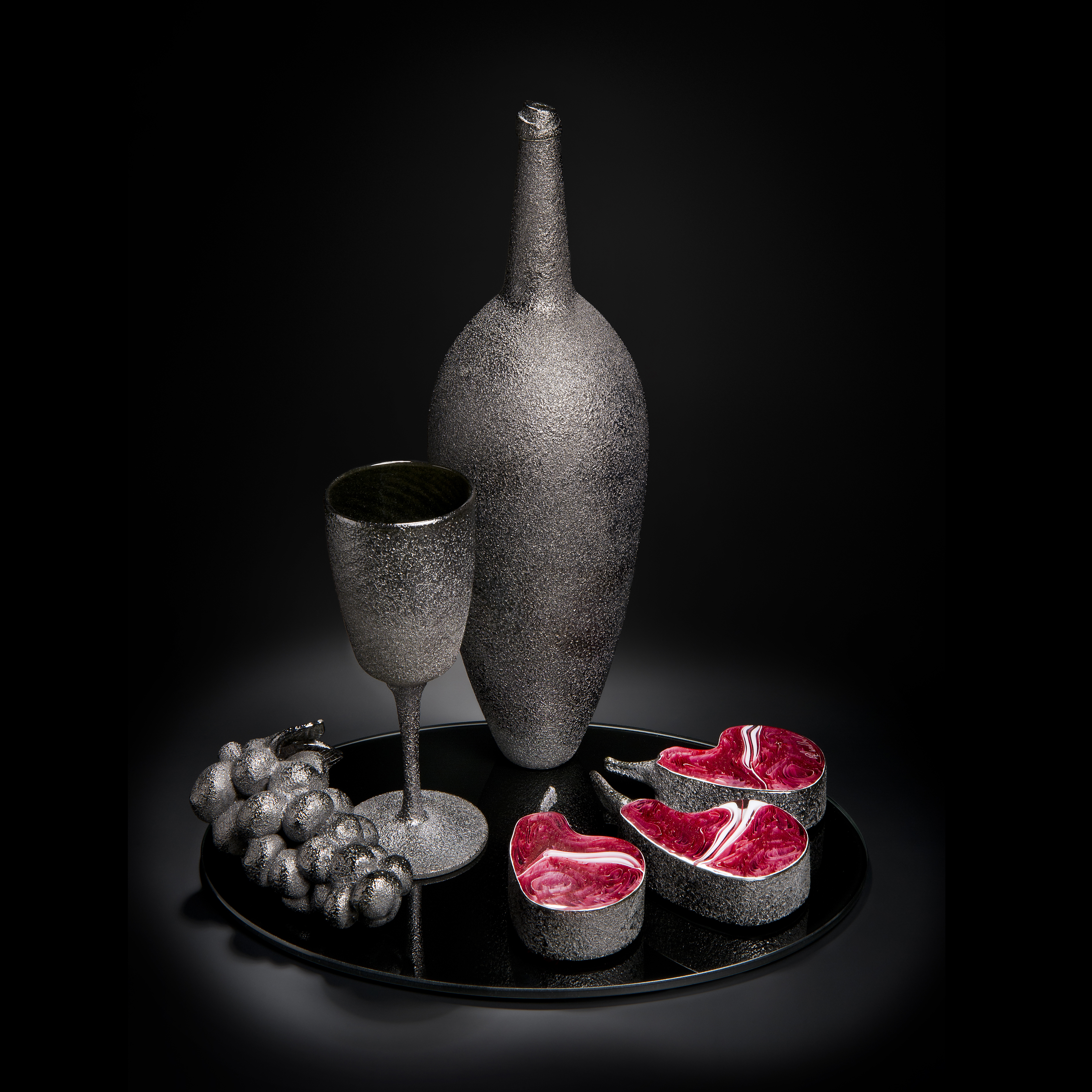 still life artwork of bowl glass grapes and cut fruit in black and dark flesh colours made from handblown and sculpted glass