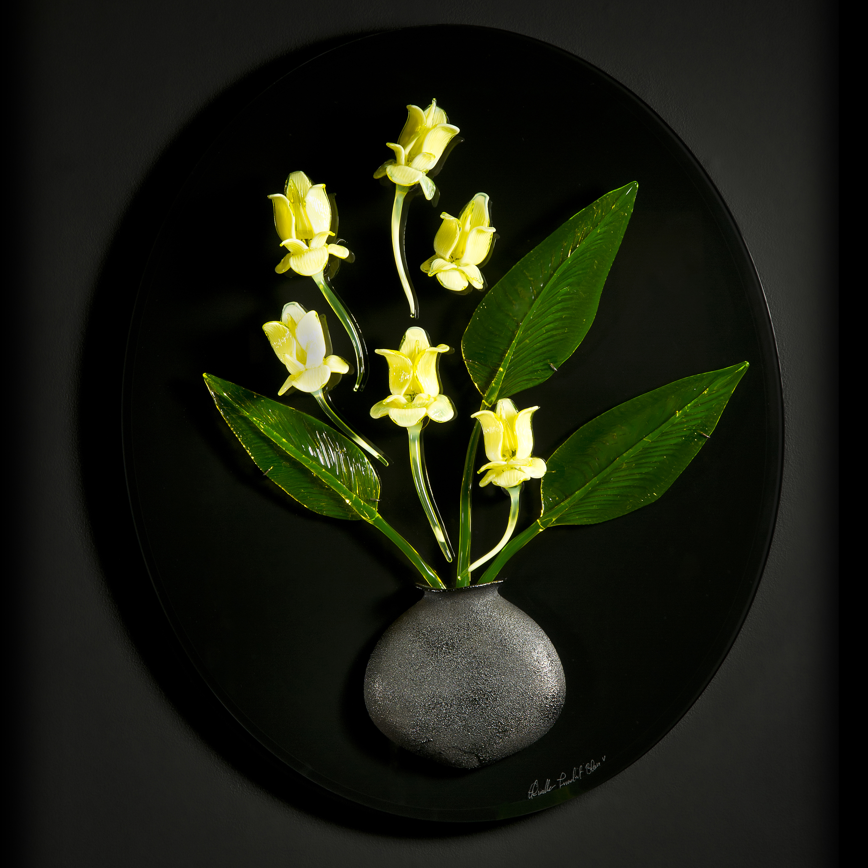 art glass wall sculpture of green leaves and yellow flowers in grey vase with black background