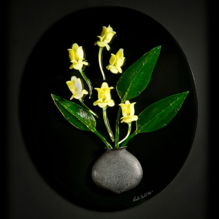 art glass wall sculpture of green leaves and yellow flowers in grey vase with black background