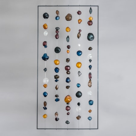 hanging art glass sculpture of brightly coloured pebble shaped glass pieces in rectangular frame