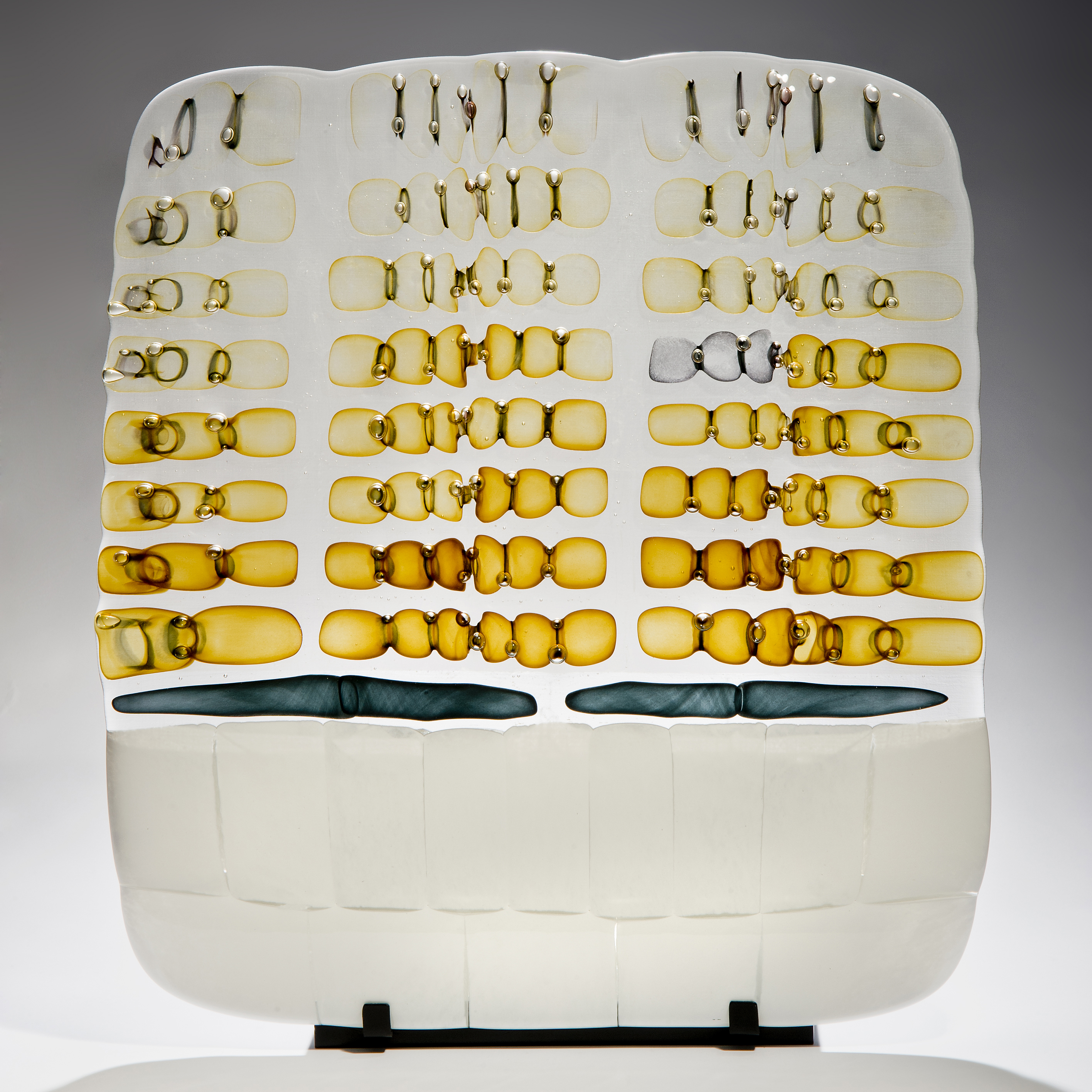 pictoral art glass sculpture in white and amber on black metal stand