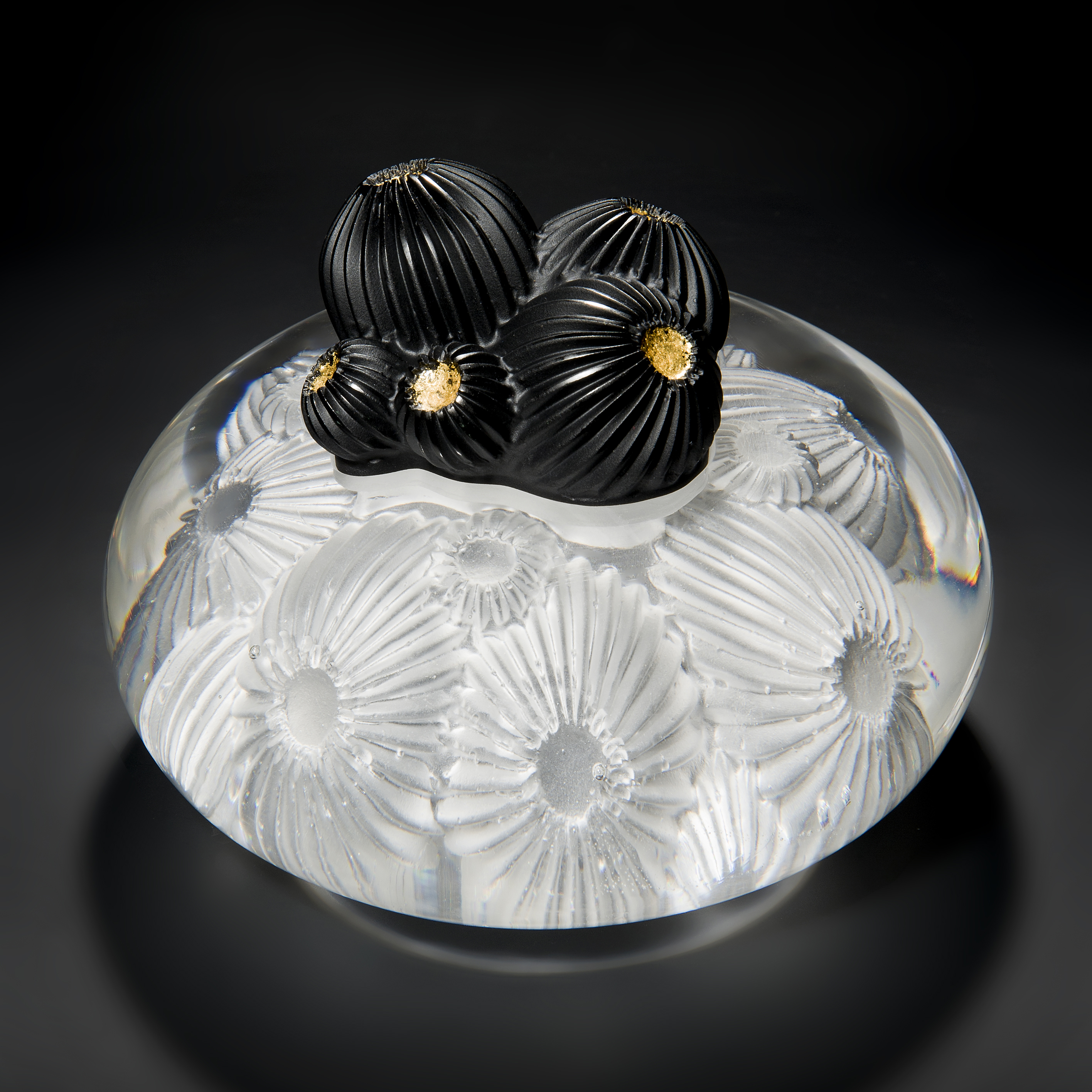 glass artwork of white star coral with round black berries in centre