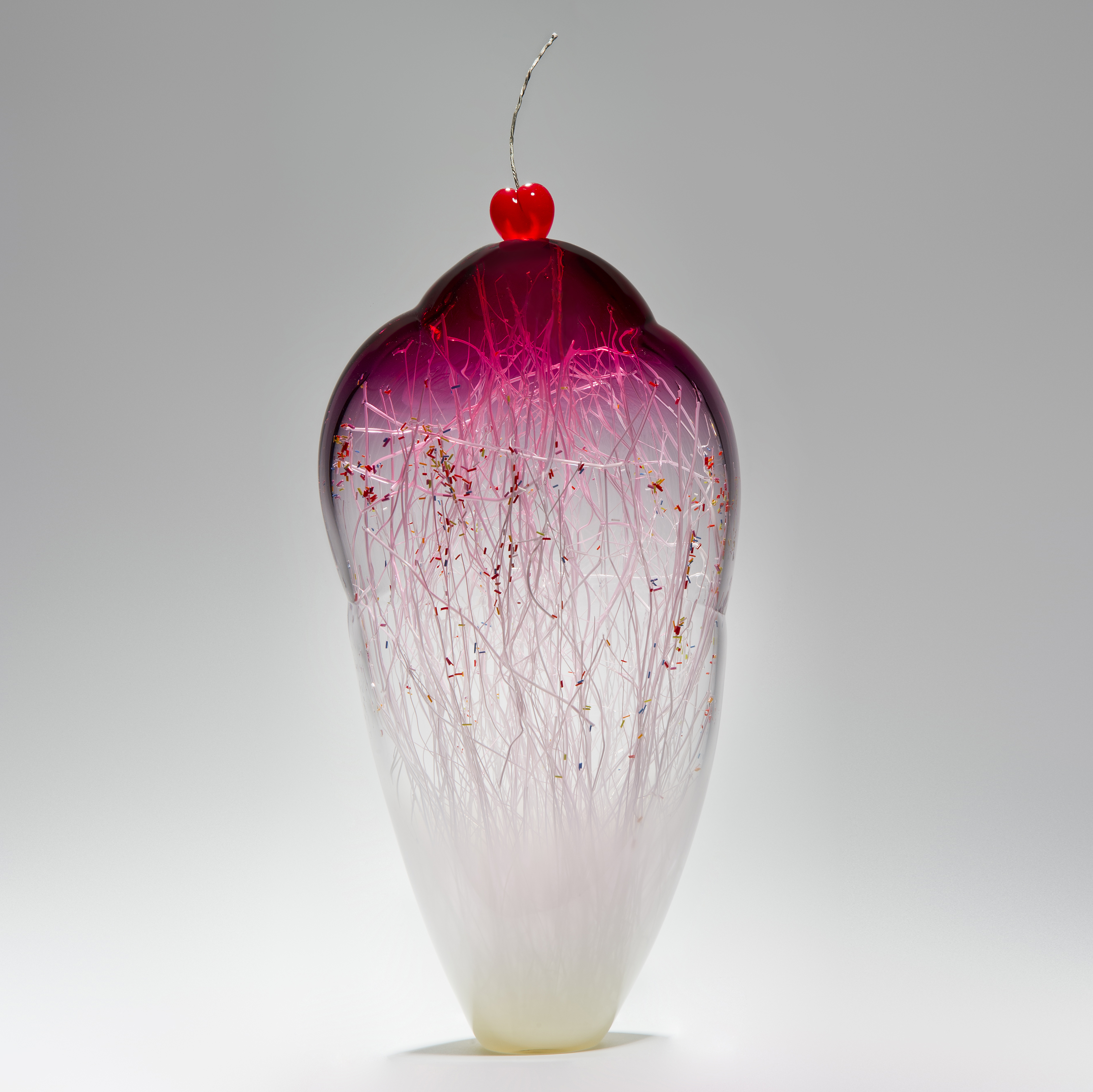 tall and thin decorative glass ornament in white and pink with natural looking internal structure and cherry on top