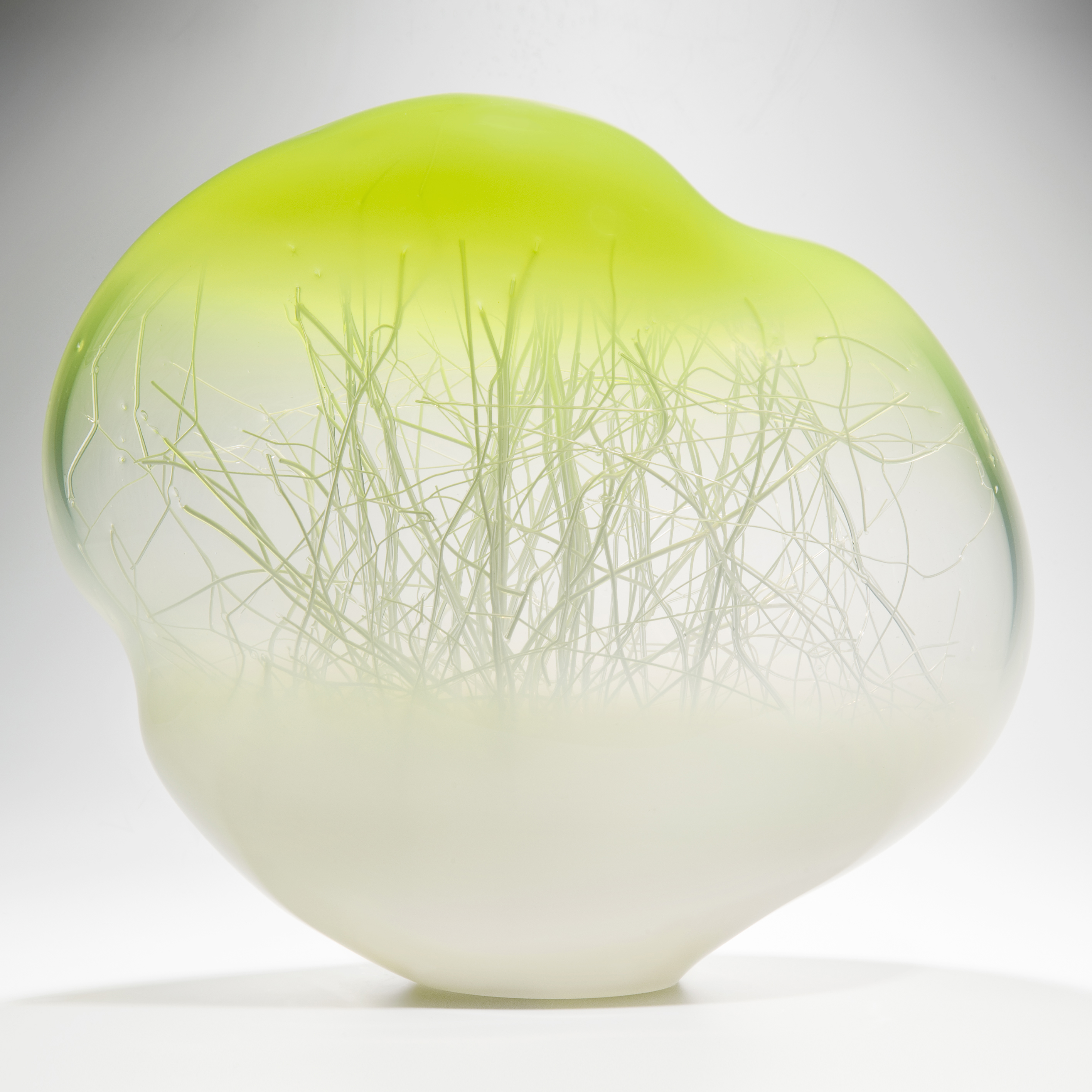 orb shaped glass art sculpture with internal tree branch like structure with white base and bright yellow top