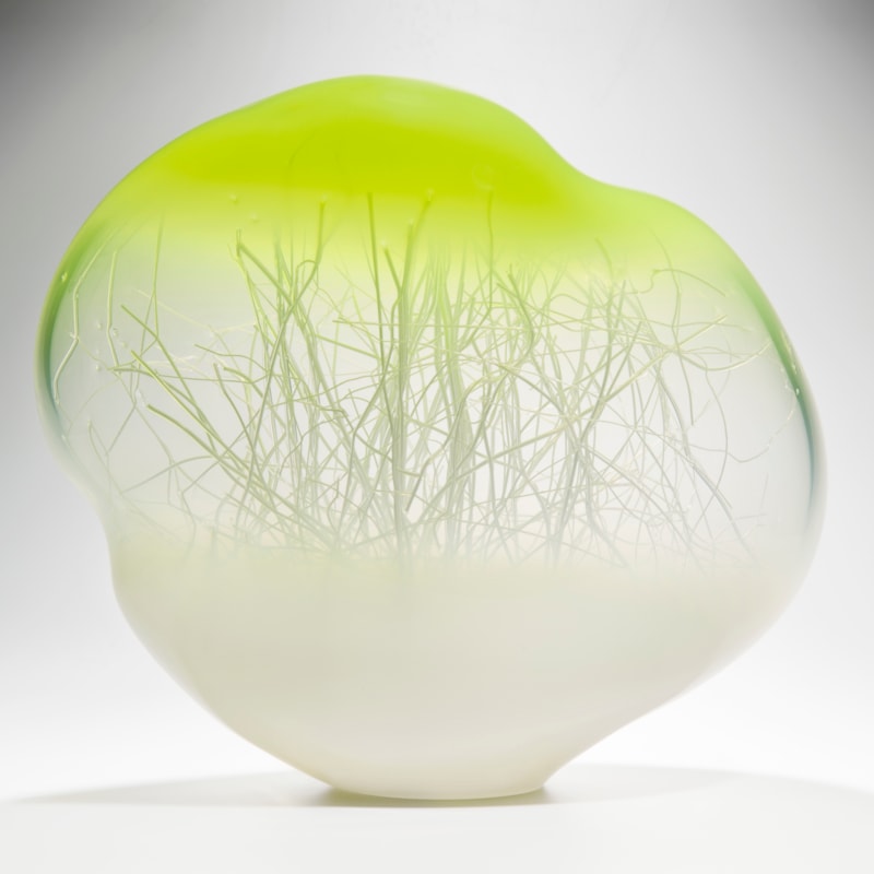 orb shaped glass art sculpture with internal tree branch like structure with white base and bright yellow top