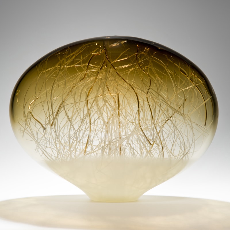 orb-shaped green and beige coloured glass sculpture with delicate nature-inspired internal structure